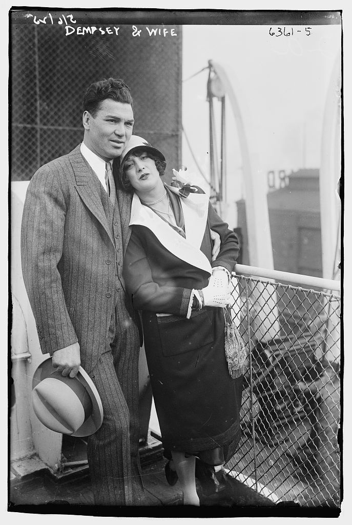 Jack Dempsey and his wife Estelle posing beside a wire fence, with the original Bain negative border and handwriting visible